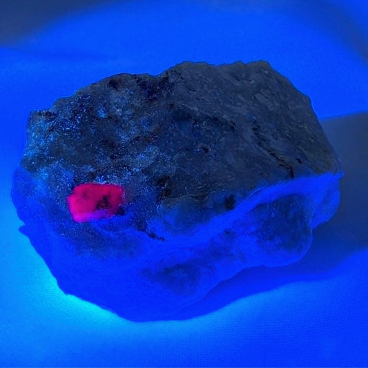 Ruby in Marble raw specimen resting on neutral champagne silk fabric.