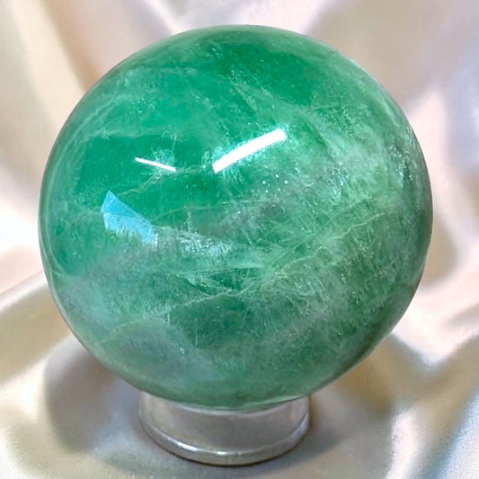 A polished 370g green Fluorite crystal sphere. This unique piece has vibrant color density and natural internal rainbow reflections. Ships from Melbourne.