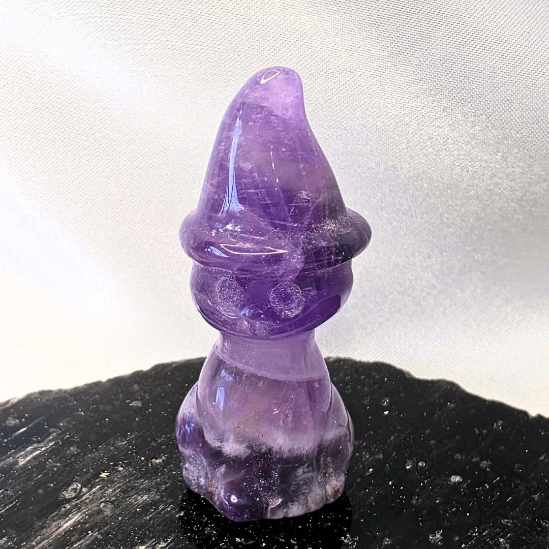 Amethyst cat figurine on a black surface with a white background