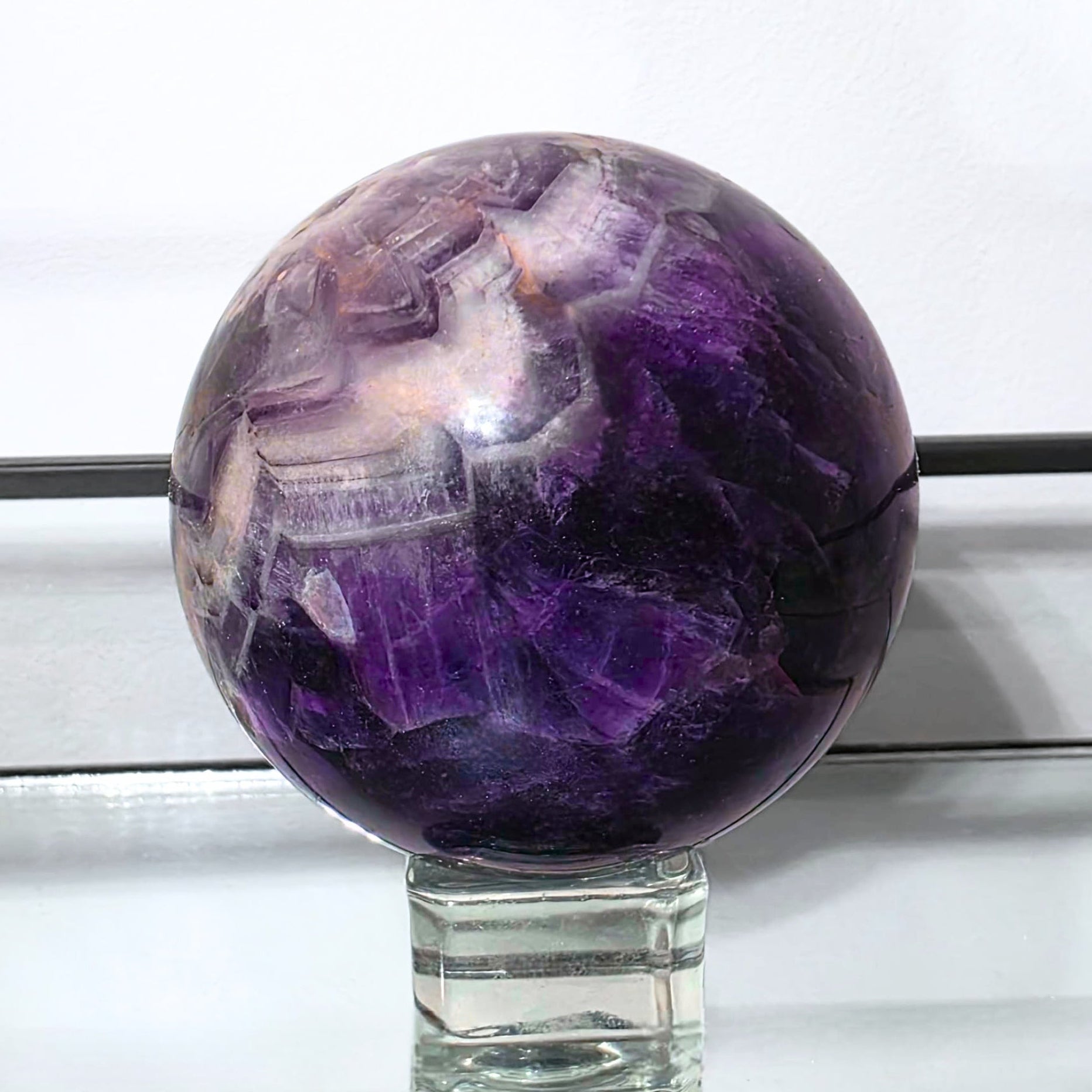 Amethyst crystal ball on a stand with a white background