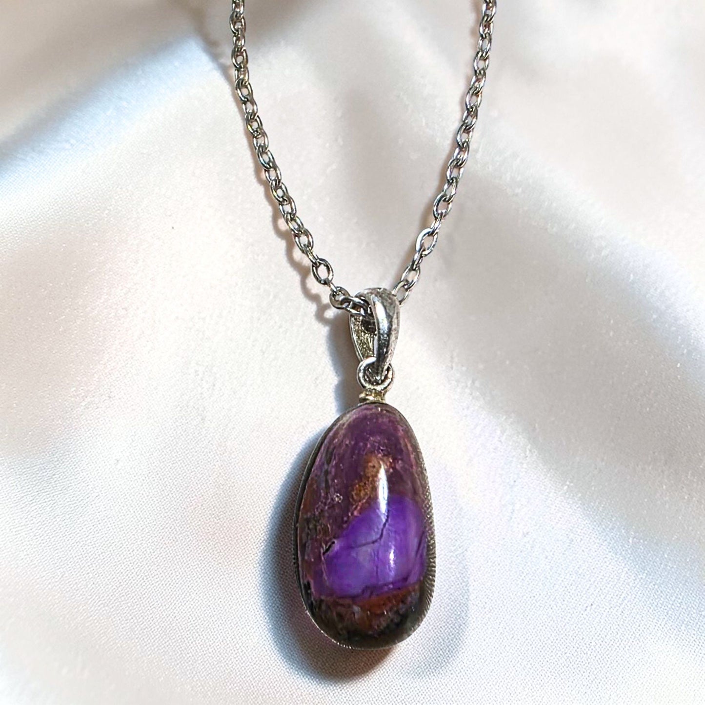 Sugilite pendant with purple matrix set in sterling silver bail on chain