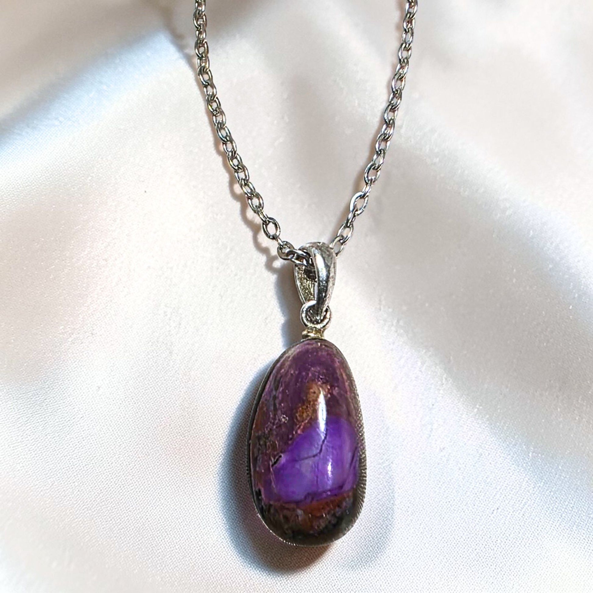 Sugilite pendant with purple matrix set in sterling silver bail on chain