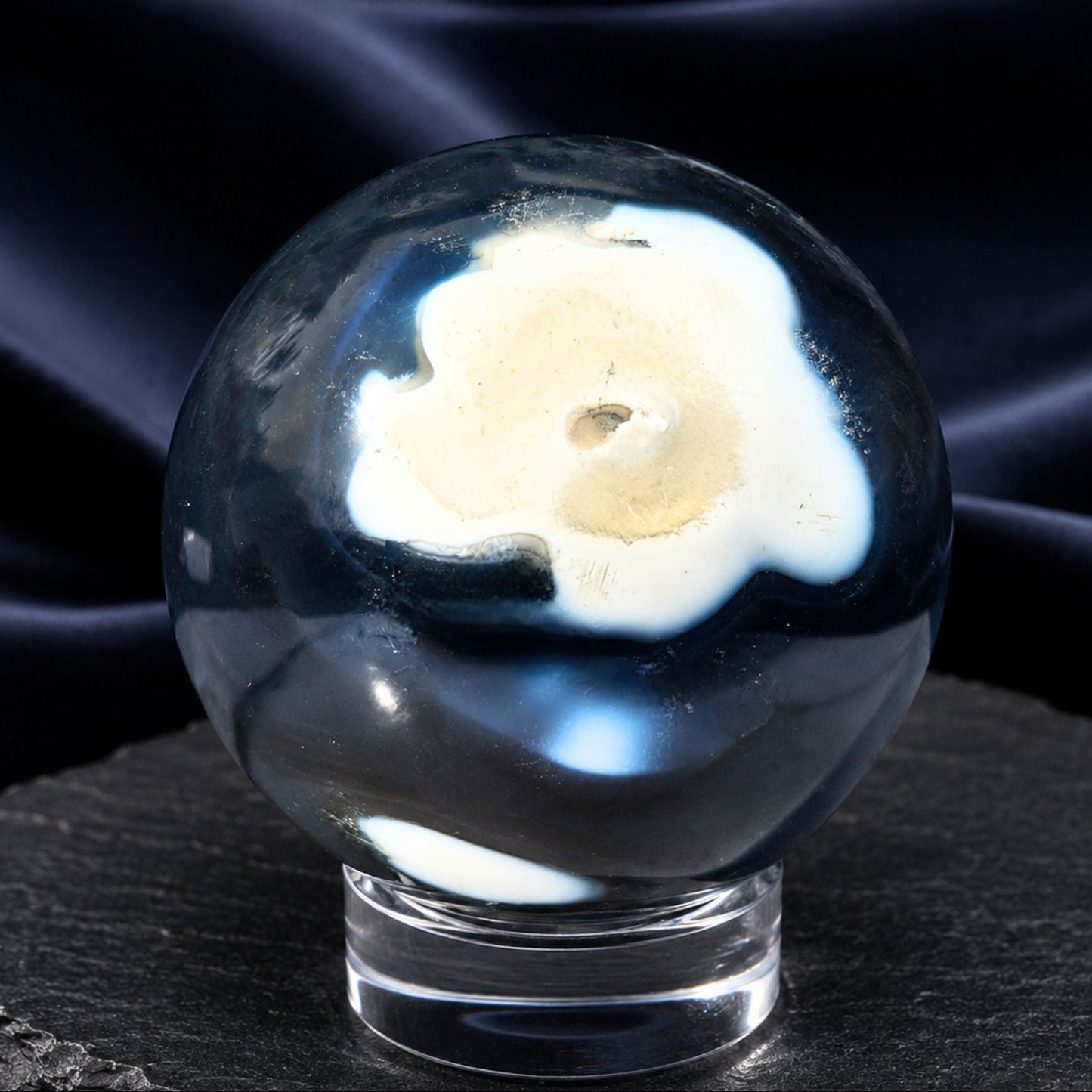 Orca Agate crystal sphere showing translucent blue-black colors, white patches, and a prominent open druzy cave.