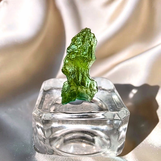 Genuine natural Moldavite specimen from the Czech Republic displayed on a clear glass stand.