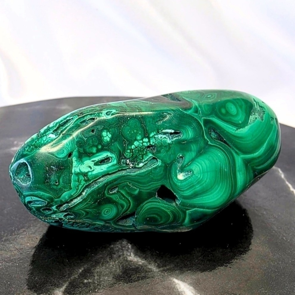 Green malachite stone on a reflective black surface with a white background