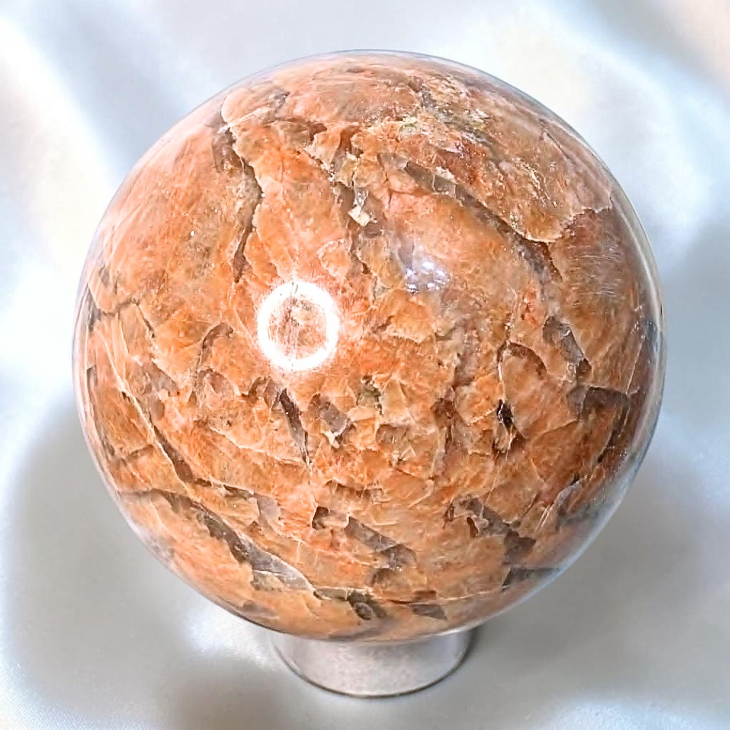 Large peach moonstone sphere with silver shimmer and natural feldspar texture on stand