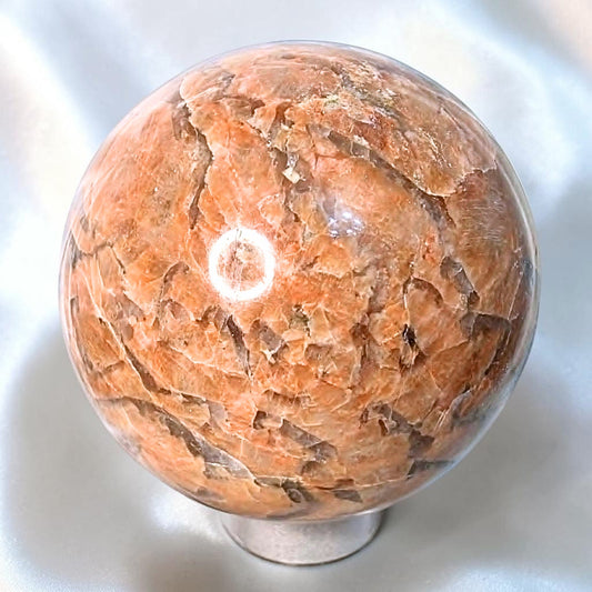 Large peach moonstone sphere with silver shimmer and natural feldspar texture on stand