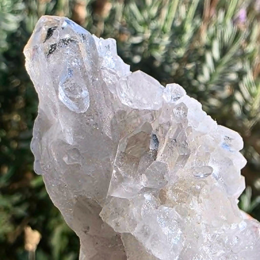 High clarity clear quartz cluster from Brazil with multiple internal rainbows and natural crystal points displayed in natural light.