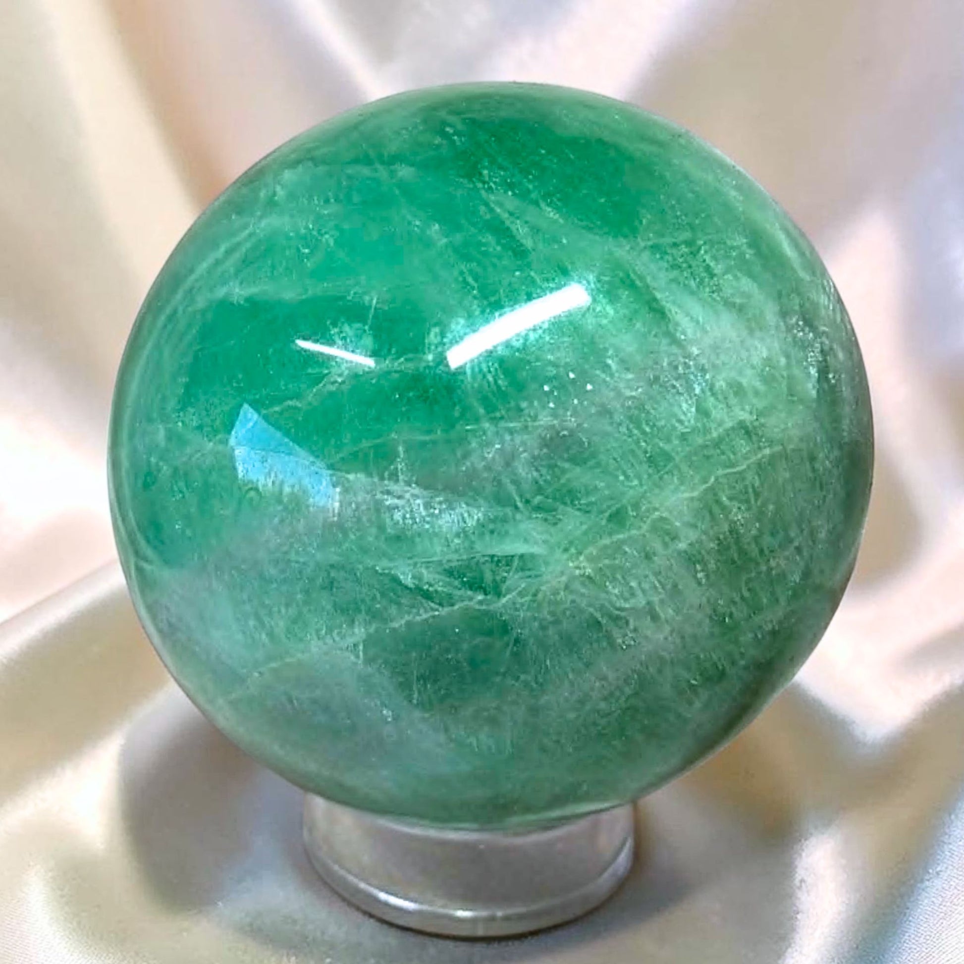 A polished 370g green Fluorite crystal sphere. This unique piece has vibrant color density and natural internal rainbow reflections. Ships from Melbourne.