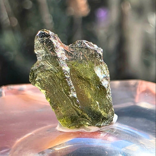 Moldavite crystal on a reflective surface