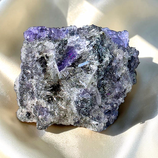 Purple-blue cubic fluorite crystals on radiating needle quartz and black druzy chalcedony mineral specimen with natural crystal formations.